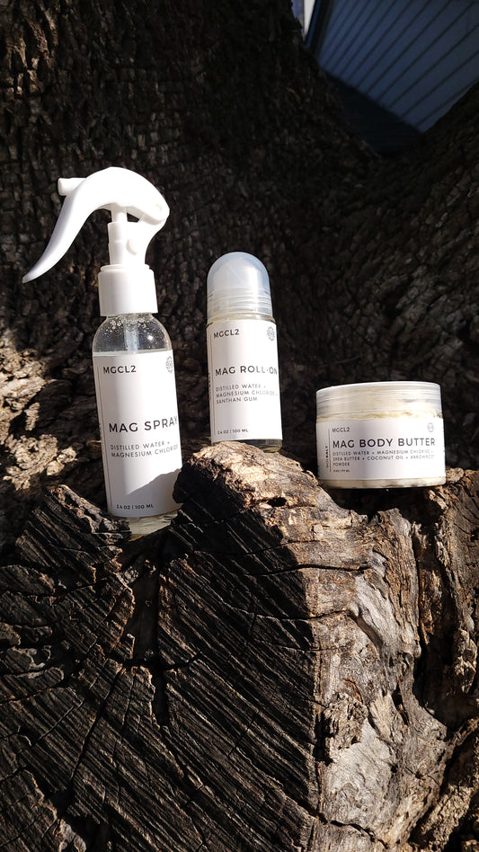 A photo of our bundle displayed on a tree that includes: the magnesium oil spray, roll-on, and body butter.